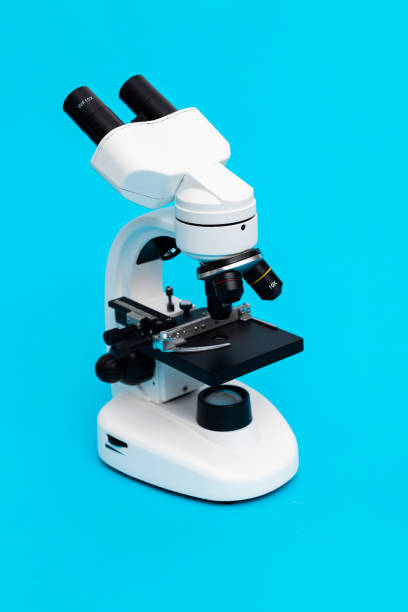 biały mikroskop na niebieskim tle - bacterium high scale magnification magnification virus zdjęcia i obrazy z banku zdjęć