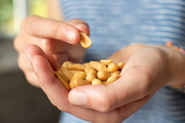 close up of teenage girl eating handful of salted peanuts - peanut food snack healthy eating imagens e fotografias de stock