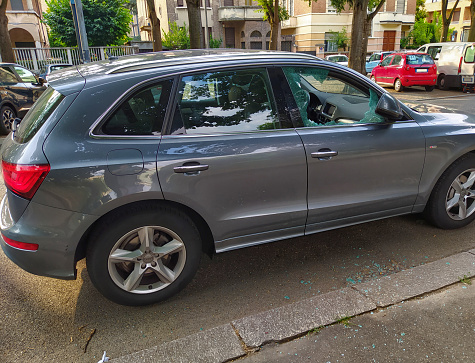 Turin,Italy.July 2020. A car has been broken into: the front right window is reduced to tiny splinters, some are on the pavement, others scattered on the dashboard. Rest of the glass is full of cracks