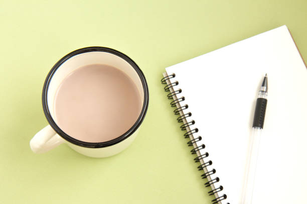 istock Notebook with pen and cup of cocoa on bright background 1261595519