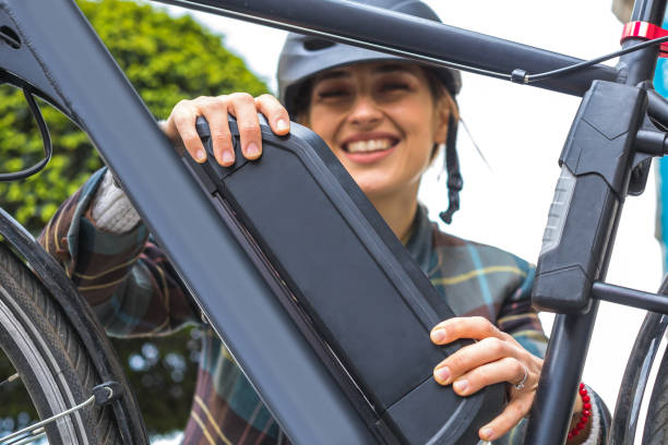 donna in possesso di una batteria per bici elettriche montata sul telaio - bicicletta elettrica foto e immagini stock
