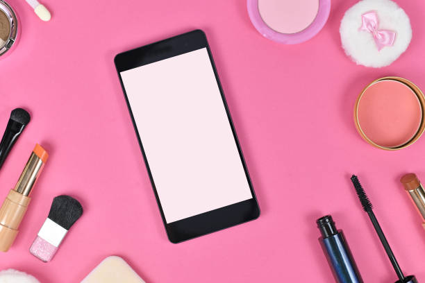 istock Flat lay with blank black smart phone with empty white screen surrounded by makeup beauty products 1261650487