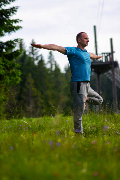 um instrutor de yoga masculino faz uma pose em um estúdio de yoga ao ar livre na natureza. - flexibility business gymnastics exercising - fotografias e filmes do acervo