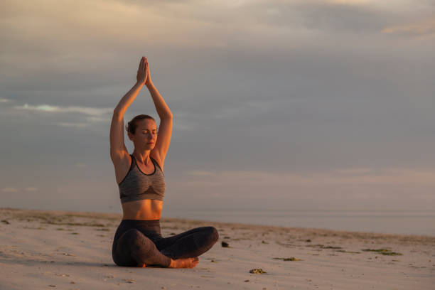 istock Woman practising yoga on the beach 1261662951