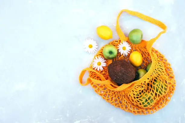 Photo of Shopping bag with fruits and chamomile flowers on a black background.