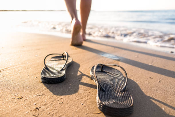 女性の足は、ビーチで海水に向かってサンダルから離れて移動します - flip flop human foot sand women ストックフォトと画像