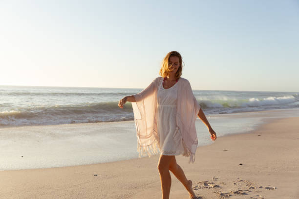istock Beautiful woman walking on the beach 1261678511