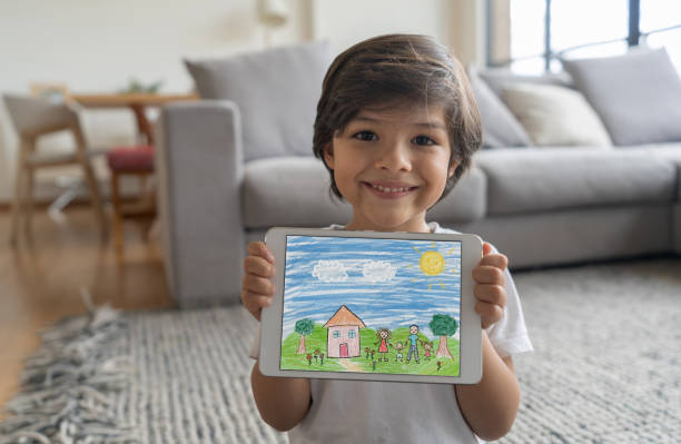 Boy at home showing a drawing on a tablet computer Happy boy at home showing a drawing he made on a tablet computer and looking at the camera smiling - lifestyle during lockdown concepts coloring photos stock pictures, royalty-free photos & images