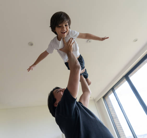istock Happy father playing airplane with his son at home 1261688256