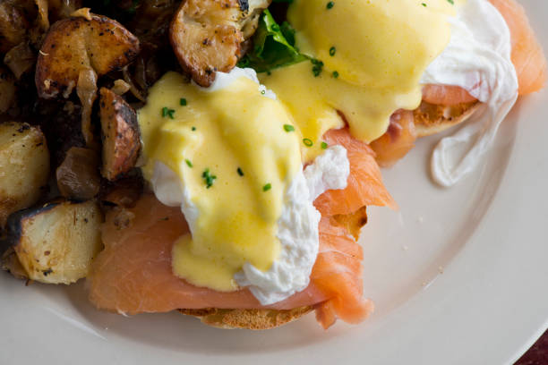 istock Eggs Benedict. Breakfast or brunch favorite: English muffin, topped w/ poached eggs, ham, lox, spinach, cheese & hollandaise sauce. Served in a cast iron skillet w/ potato hash. Classic French bistro or American restaurant entree. 1261690343