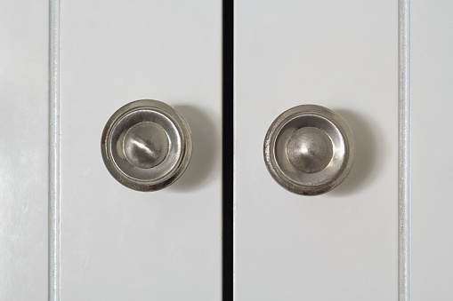 Round knobs on white cupboard door in natural window light.