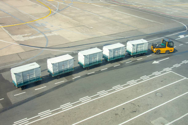 puste wózki bagażowe na lotnisku, do rozładunku bagażu samolotu pasażerskiego, wśród ogonów samolotów. - luggage cart airport luggage cargo container zdjęcia i obrazy z banku zdjęć