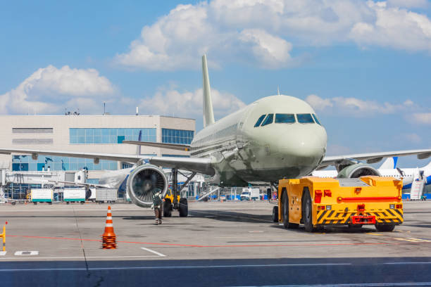 istock Towing a passenger plane using special equipment for aircraft maintenance. Departure flight in the background of the terminal building. 1261704249