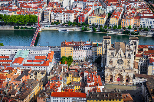 Aerial view of Lyon cityscape with St Jean Cathedral monument in foreground along Saone riverbank and red rooftops from large Place Bellecour famous town square. Photo taken in Lyon city, Unesco World Heritage Site, in Rhone department, Auvergne-Rhone-Alpes region in France, Europe during a sunny summer day.