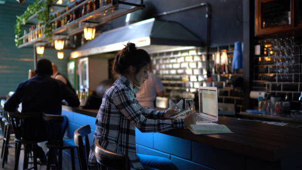 istock Young woman working or studying in a bar, using laptop and smartphone 1261716763