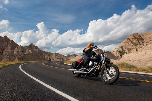 motorcyclist in a motorcycle jacket and tinted helmet with a classic motorcycle in nature. Stylish biker