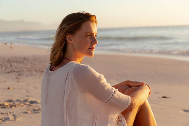 istock Beautiful woman sitting on the beach 1261744116