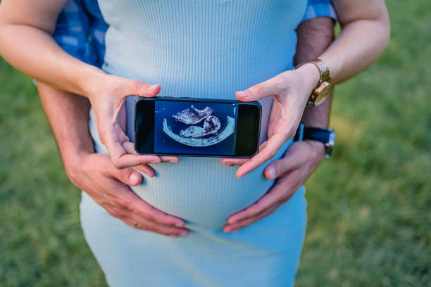 schwangeres paar hält ultraschallbild auf dem smartphone - human pregnancy telephone ultrasound family stock-fotos und bilder