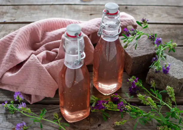 Fresh lavender syrup in decorative preserving bottles filled on wood