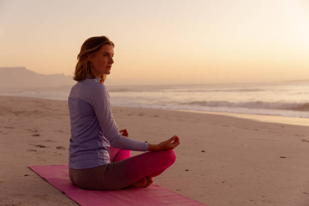 istock Woman performing yoga on the beach during sunset 1261748210
