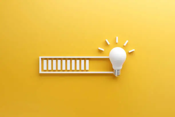 Photo of Loading bar almost complete with idea beeing processed on a light bulb on yellow background.