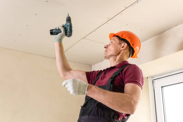 istock Worker is using screws and a screwdriver to attach plasterboard to the ceiling. 1261760655