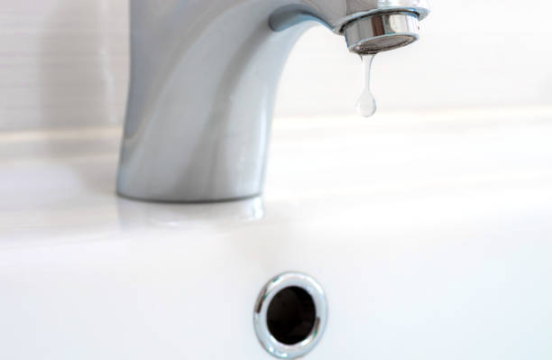 istock Faucet with a drop of water against a white sink. 1261781790