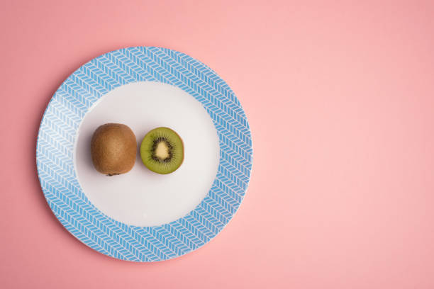 istock Kiwi and a half on dish over pink flat lay 1261795721