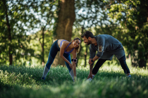 istock Young couple doing warming exercise in nature, they smiles and look at each other 1261797158