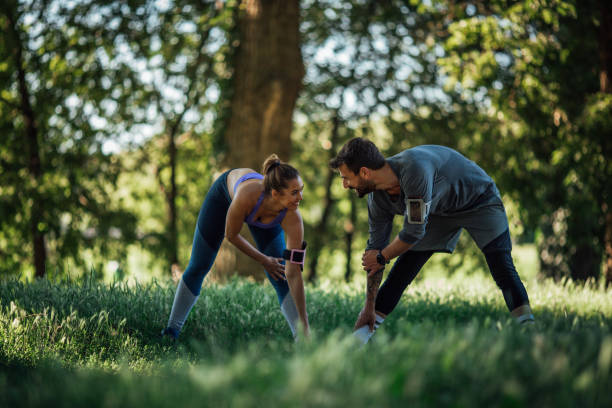 istock Young couple doing warming exercise in nature, they smiling and look at each other 1261797708