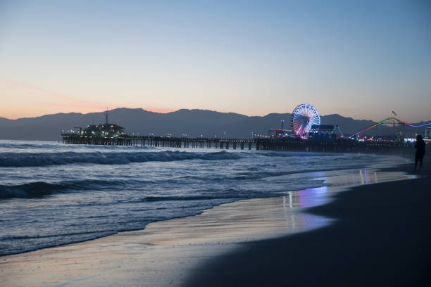 twilight and reflections of the santa monica pier from the beach - santa monica beach beach california wave imagens e fotografias de stock