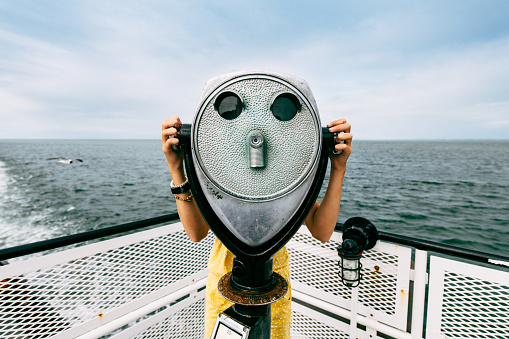 Girl looking though coin operated binoculars on free public ferry service to the Outer Banks in North Carolina.