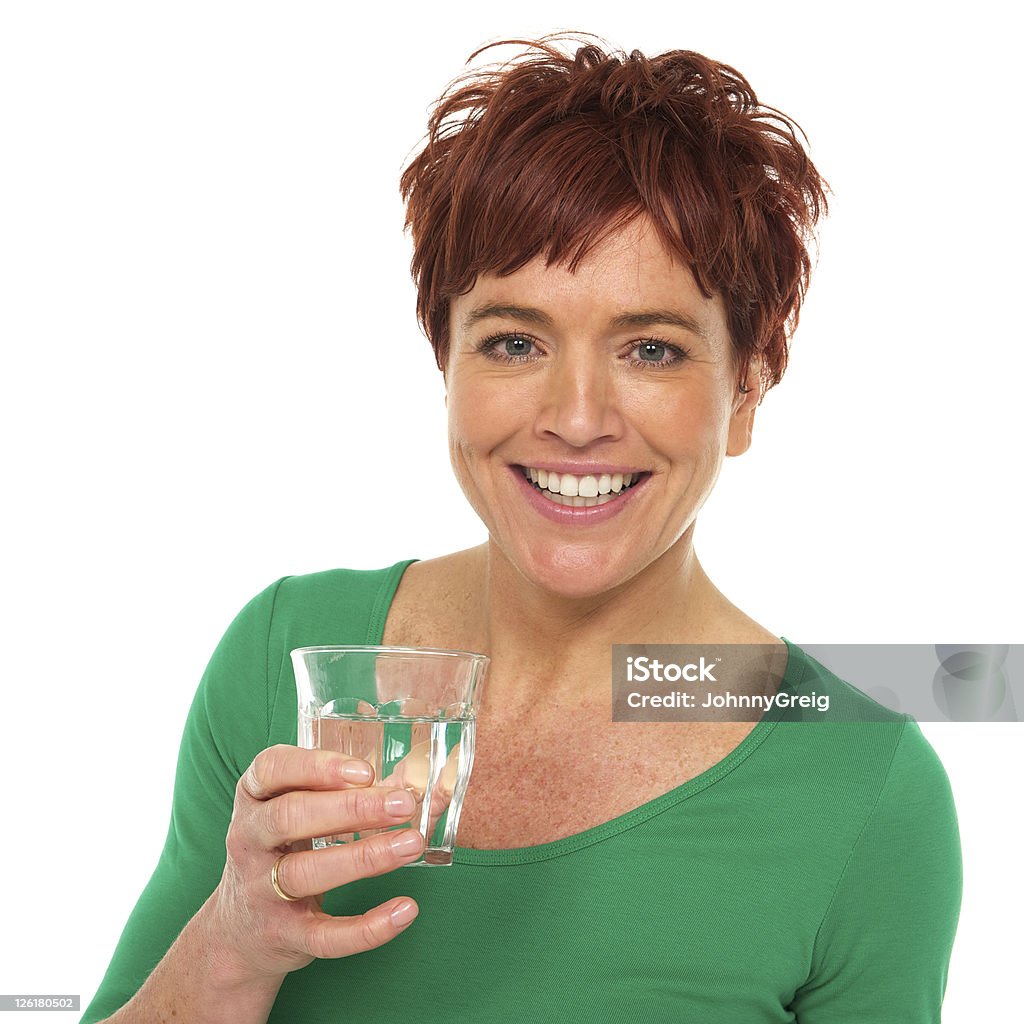 Mujer sonriendo en camisa verde cuenta con un vaso de agua. - Foto de stock de 40-44 años libre de derechos