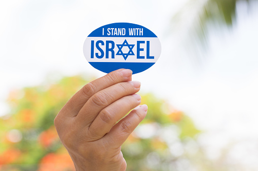 Hand holding I stand with Israel sticker