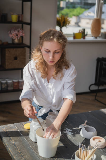 istock Female potter making ceramic dishes at her studio. Working process of glazing ceramic bowl 1261815356