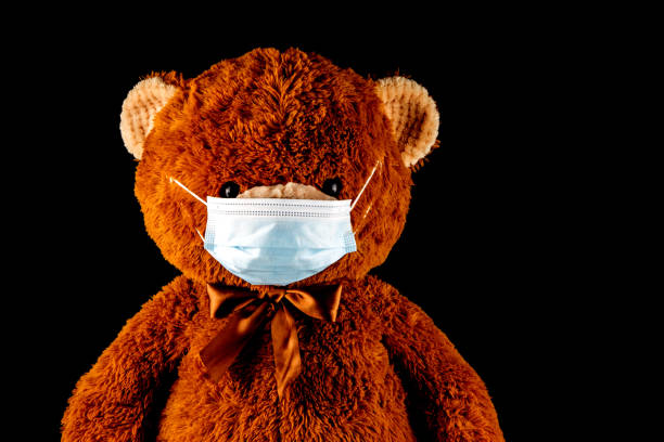 istock Teddy Bear Wearing a Face Mask on a Black Background 1261823082