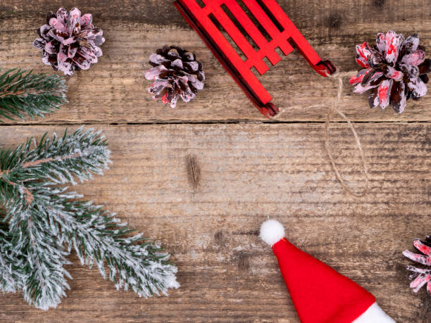 istock Christmas tree branch under the snow, cones, red sledges and Santa's hat. 1261828501