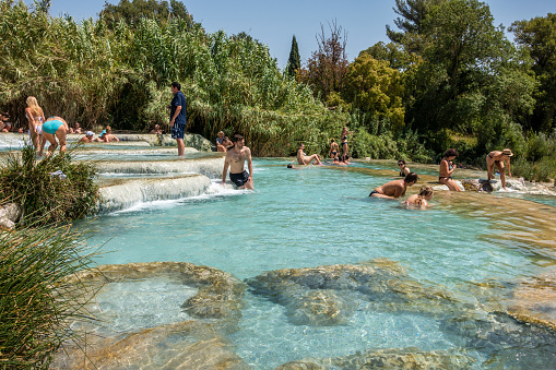Saturnia, Italy - August 4, 2017: People visit natural hot springs in Saturnia, Italy. Thermal springs of Saturnia are a natural attraction of Southern Tuscany.