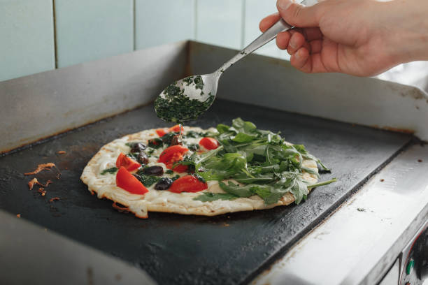 cooking handmade italian piada with pesto and tomatoes