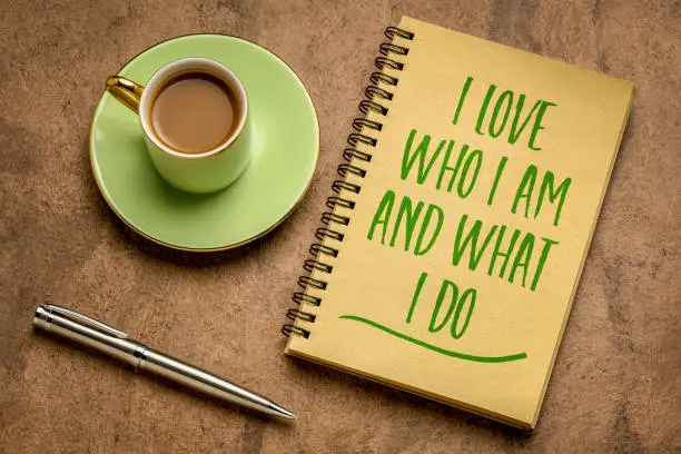 I love who I am and what I do - positive affirmation words in a spiral notebook with a cup of coffee, self esteem and personal development concept