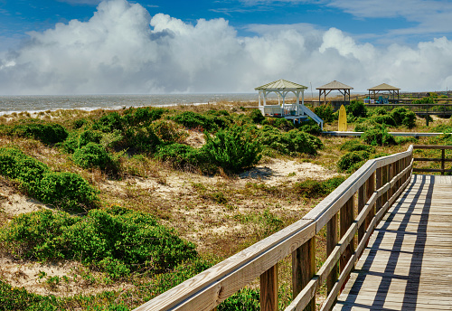 A beautiful landscape of gazebos by a beach boardwalk with the ocean in the background.