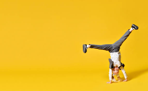 Active happy girl child upside down on yellow background stock photo