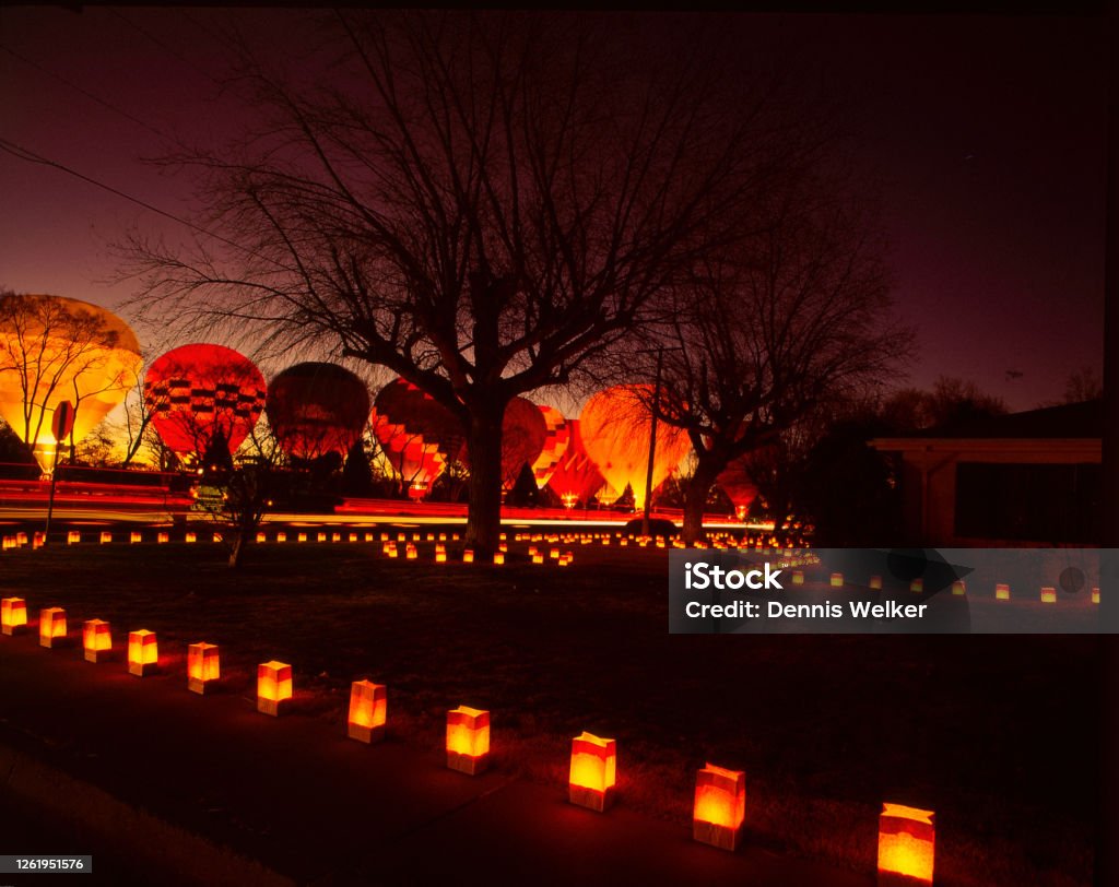 Hot Air Balloons Glow at Christmas Eve Backlit Hot Air Balloons glow in the night as the sunsets in New Mexico, in Albuquerque Old Town with luminaries lighting the ground on Christmas Eve New Mexico Stock Photo