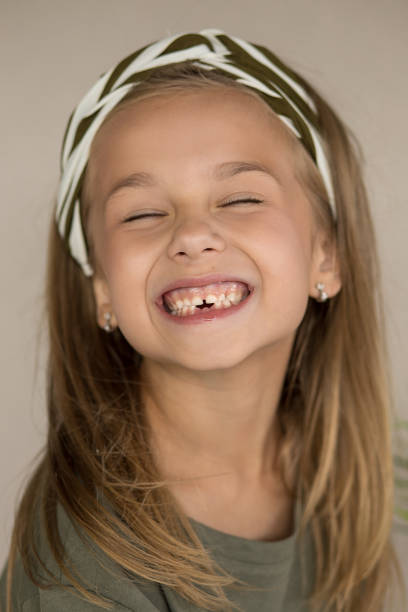 foto di una bella ragazza dagli occhi marroni senza denti di 6 anni. il sorriso di un bambino senza due denti inferiori. divertente ritratto ravvicinato di bambino. odontoiatria pediatrica. - toothless smile foto e immagini stock