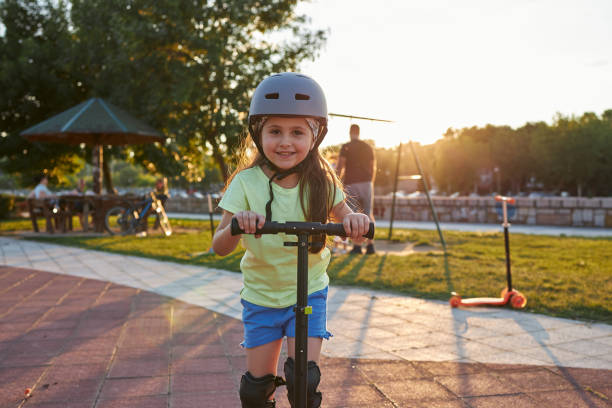 istock Beautiful female child on a push scooter wearing a protective helmet 1261978061