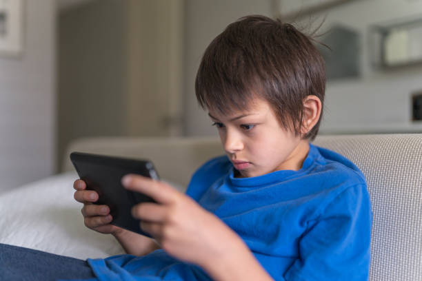 istock Nine-year old ethnic boy plays game on phone 1262025838