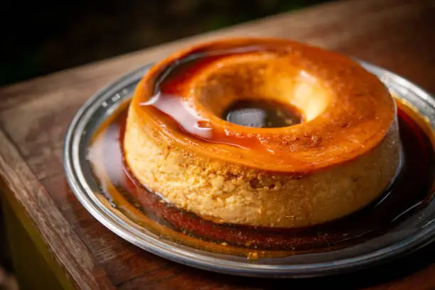 Photo of Brazilian gastronomy. Milk pudding with caramelized syrup on wooden table.