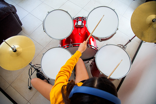 teenage woman playing drums at home