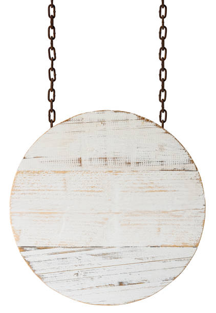 istock Old weathered circular white wood sign/signboard panel with rounded sides, hanging by old rusty chains against an isolated white background. Clipping path included. 1262072945