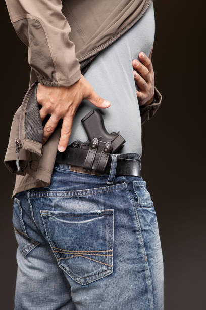 istock Holding back jacket and drawing pistol from a concealed carry holster. 1262078720